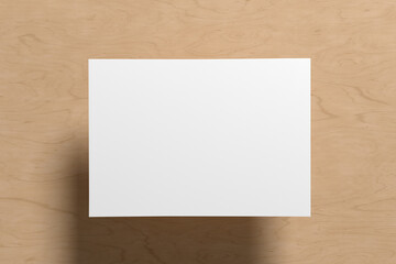 A sheet of paper mock up floating above the wooden table table.