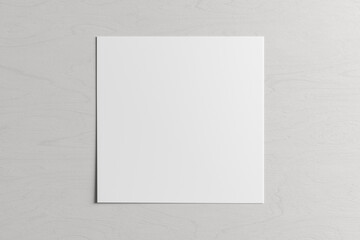 Square sheet of paper on the white wooden table.