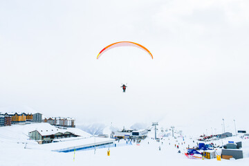 Gudauri ski resort panorama with tandem paragliders fly over skiers in ski resort in cold winter day