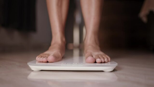 Woman on scales measure weight. Female dieting checking BMI weight loss. Cinematic 4K