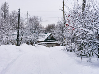 A road covered in snow. There is a house in the background, which the road is leading to