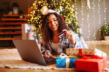Young woman with credit card, gifts, and laptop. Online shopping at Christmas holidays. 