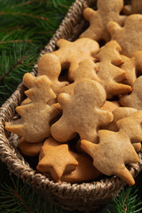 Fresh Christmas gingerbread cookies in a wicker basket and fir tree branches. Christmas homemade bakery.