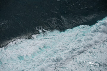 The waves of the ocean water meet with underwater pointed rocks