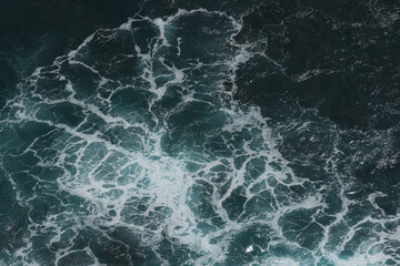 The waves of the ocean water meet with underwater pointed rocks