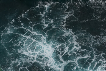 The waves of the ocean water meet with underwater pointed rocks