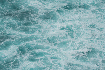 The waves of the ocean water meet with underwater pointed rocks