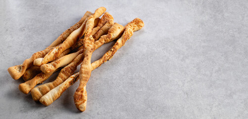 Crispy bread sticks with parmesan, grissini, on gray stone background, banner, place for text