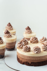 Layered dessert Trifles in a transparent glass.  Sponge biscuit and three chocolate mousse layers. Chocolate souffle trifle cake in individual disposable transparent cups. White background