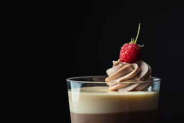 Layered dessert Trifles decorated with raspberry.  Sponge biscuit and three chocolate mousse layers. Chocolate souffle trifle cake in individual disposable transparent cups. Black background