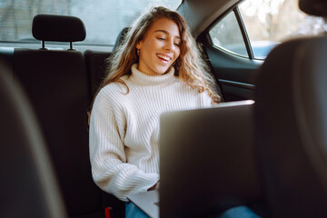 Beautiful and confident woman  working on laptop while sitting in the car. Business concept. 