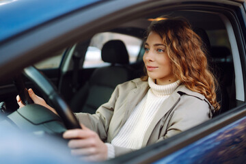 Young woman driving a car in the city. Car sharing, rental service or taxi app.