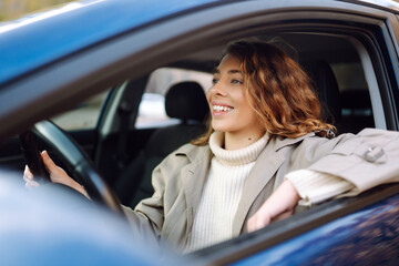 Young woman driving a car in the city. Car sharing, rental service or taxi app.