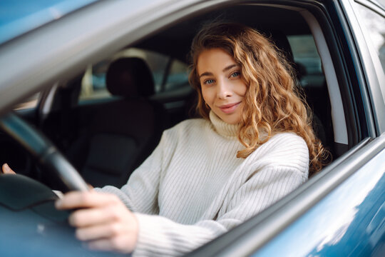 Young woman driving a car in the city. Car sharing, rental service or taxi app.