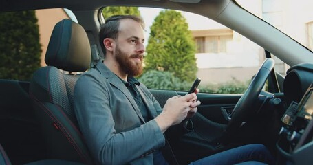 Serious business man working with cellphone in modern car. Focused male professional chatting using phone at car. Man writing message on mobile phone in business car.