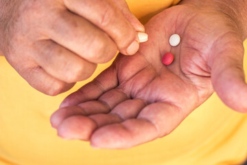 Close up view of senior woman holding vitamins and minerals pills in hand
