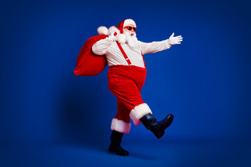 Full length body size view of his he attractive cheerful cheery funny fat Santa carrying big large...