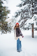Fototapeta na wymiar Happy woman enjoying first snow in the forest. Holidays, rest, travel concept