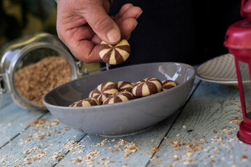 Sweet chocolate cookies on rustic wooden table with flakes. Woman hand holding cookies