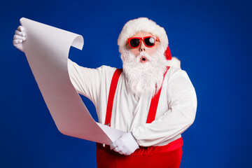 Portrait of his he attractive amazed fat white-haired Santa holding in hands reading wish present gift list pout lips order isolated bright vivid shine vibrant red burgundy maroon color background - obrazy, fototapety, plakaty