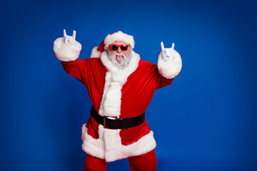 Portrait of attractive crazy cheerful childish Santa showing horn symbol having fun isolated over...
