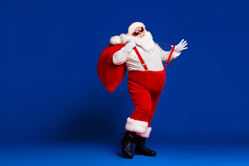Full length body size view of his he attractive childish cheerful cheery funny fat Santa carrying...