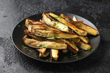 Roast eggplant, aubergine with herbs on black plate