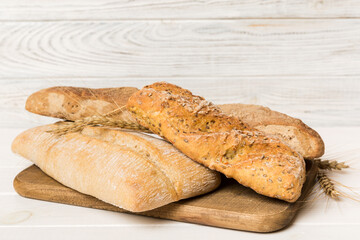 Freshly baked bread on cutting board against white wooden background. perspective view bread with copy space