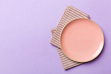 Top view on colored background empty round pink plate on tablecloth for food. Empty dish on napkin with space for your design