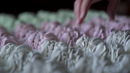 Pastry chef puts ready-made marshmallow sprinkled with powdered sugar on a board