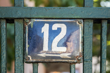 Weathered grunge square metal enameled plate of number of street address with number 12
