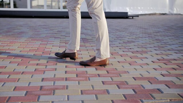 A man in a suit slowly walks down the sidewalk. Men's shoes close-ups while walking (slow motion)