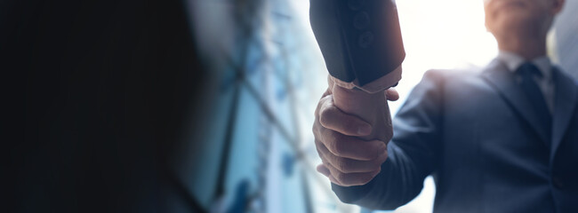 Businessmen making handshake with partner, greeting, dealing, merger and acquisition, business cooperation concept, panoramic banner, copy space for business, finance and investment background