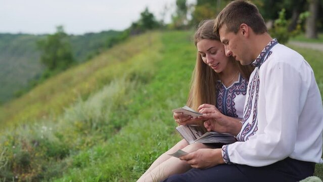 Couple sitting on a hill Family looking at their photo album sitting in the park