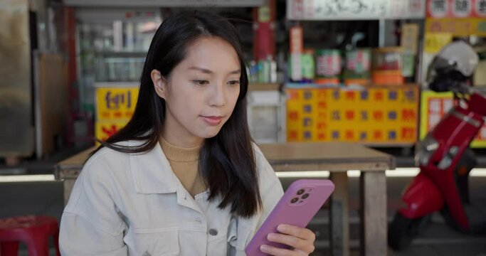 Woman use mobile phone at local food stall at Taiwan