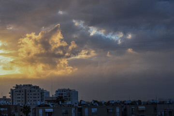 Sunset over the city. View of the city against of large fluffy clouds. Background. Israel.