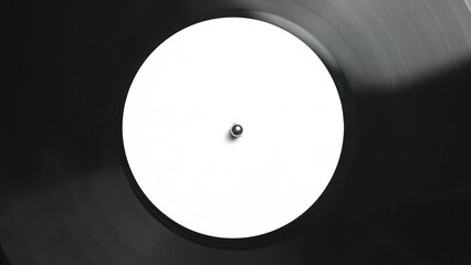Analog vinyl record with music spinning on a turntable. Classic black 12 inch disc filmed on a player directly from above in flat lay style