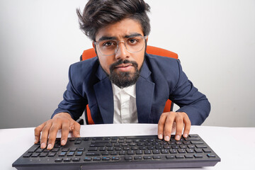 indian Man in glasses working at the computer, his hands hover over the keyboard while typing, isolated on white background. Front view.