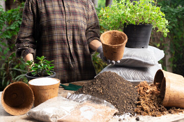 Gardening concept. A young woman mixes potting soil, prepares the soil for planting and puts it in a pot made of natural materials.