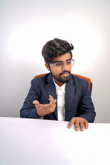 indian young business man on chair table talking to someone or explaining something to someone