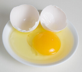 Egg yolk and shell on a plate isolate on a white background