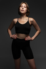 Fototapeta na wymiar Young woman in black shorts and top posing in the studio