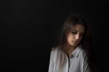 Low key studio portrait of sad girl. Horizontally. 