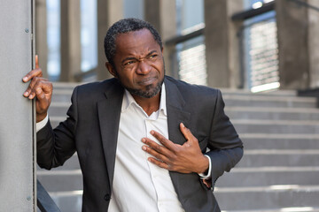 Heart attack , african american businessman has severe chest pain , man holding his hands over...