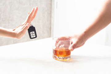 Don't drive after drinking. A car key is being held in the hand of a lady who is denying drinking.