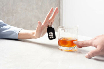 Avoid drinking and driving. A woman's hand trying to deny the alcohol is gripping a car key.