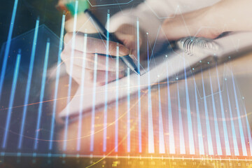 Financial forex graph displayed on hands taking notes background. Concept of research. Double exposure