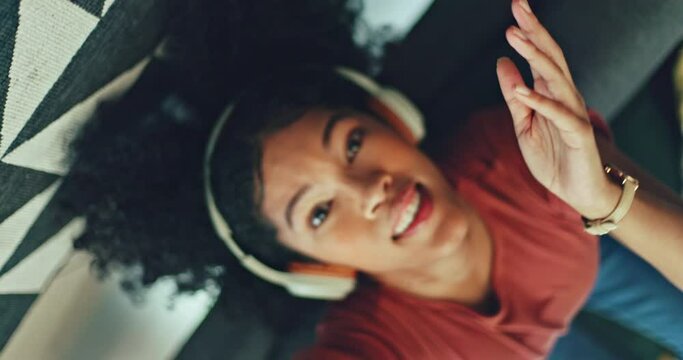 Music, headphones and black woman dance on a sofa singing with a streaming subscription service and technology. Gen z girl portrait relax on couch in living room dancing and listening to online audio