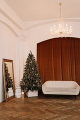 The concept of the Christmas interior. The interior of a living room with a sofa and a decorated Christmas tree with decorative elements in a vintage luxury interior in retro style in apartments