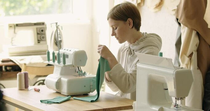 Creating new fashionable styles. Woman sewing while sitting at her working place